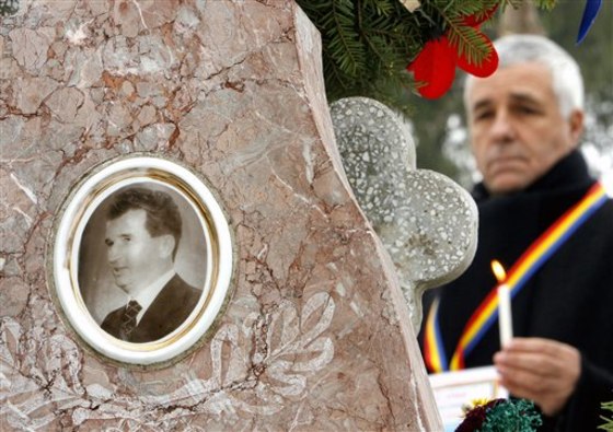 A man stands with a lit candle next to the grave of late communist dictator Nicolae Ceausescu in Bucharest last year to commemorate 20 years since his execution.